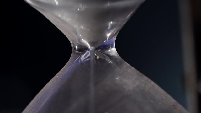 White Sand Falling on Pile in Classic Hourglass Measuring Time Passage