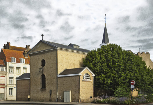 Chapelle Notre-Dame des Dunes, historic Catholic chapel in Dunkirk, France, with traditional brick architecture and elegant bell tower under a cloudy sky.