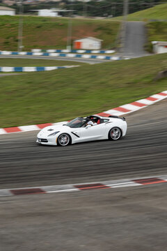 White Chevrolet Corvette C7 side profile moving fast, American sports car cornering on race track