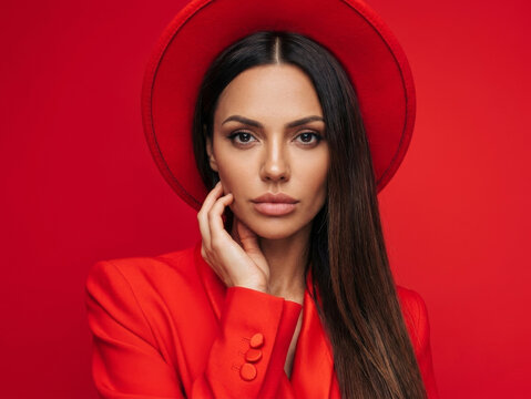 Bold and striking fashion portrait of a confident woman in a vibrant red wide-brimmed hat and matching red blazer