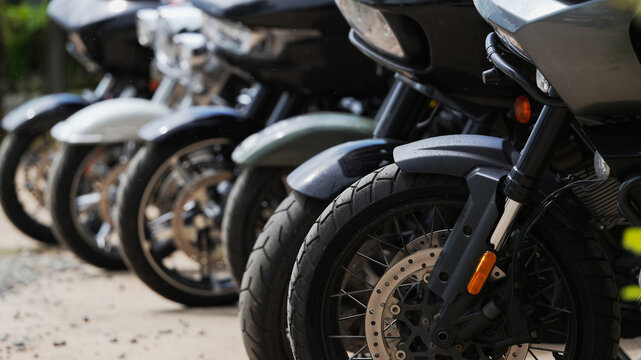 Front wheels of touring motorcycles parked in a row with selective focus