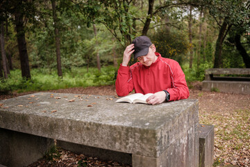 Fototapeta premium Man reading book in park thinking deeply