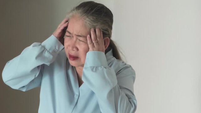 Serious and stressful Asian senior woman having stress-type headache and muscle tension health problem, concept image for physical and mental health care