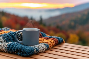 Fototapeta premium Autumn coffee mug on a cozy knitted blanket with a warm fall mountain landscape