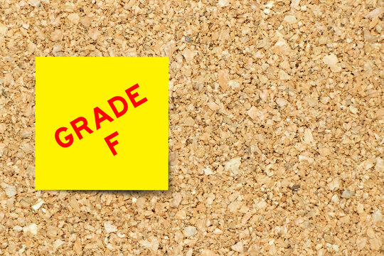 Yellow note paper with word grade F on cork board background with copy space