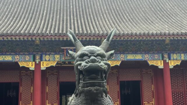 Bronze dragon statue at entrance of traditional Chinese temple. Ancient architecture in Beijing. Cultural heritage and historical landmark. Symbol of mythology and oriental art concept in China.