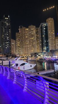 City skyline by the waterfront with yachts at night and tall buildings in Dubai