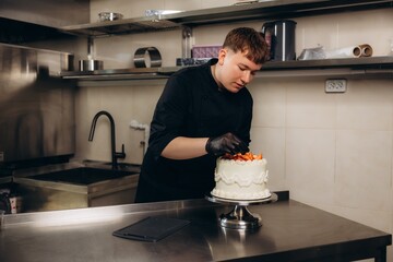 Pastry chef decorating cake with strawberries in commercial kitchen