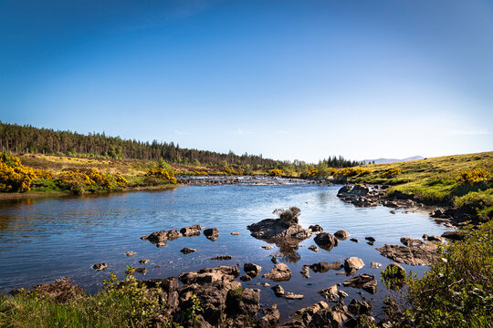 A bright, summer HDR landscape image of the salmon river, the River Naver, flowing through Strathnaver, Sutherland, Scotland.