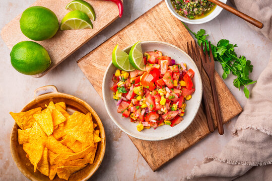 Freshly made pico de gallo with corn and lime wedges served with tortilla chips