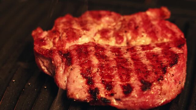Juicy steak sizzling on a hot grill with visible grill marks and smoke