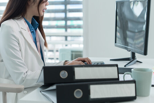 Young Businesswoman Working at Office Desk While Managing Documents and Mobile Communication.
