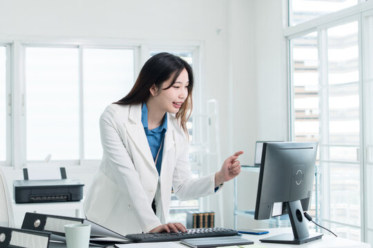 Young Businesswoman Working at Office Desk While Managing Documents and Mobile Communication.
