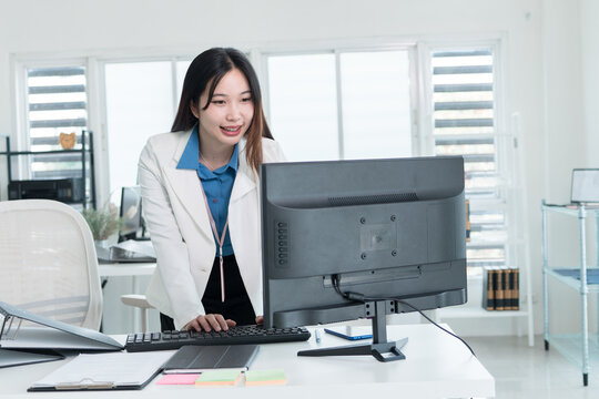 Young Businesswoman Working at Office Desk While Managing Documents and Mobile Communication.