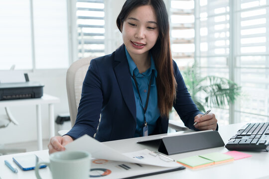 Young Businesswoman Working at Office Desk While Managing Documents and Mobile Communication.