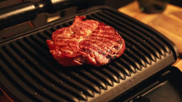 Juicy steak sizzling on a hot electric grill with perfect sear marks