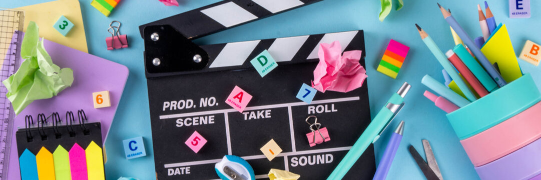 Back to School Movie Marathon background. Various colorful School and Education Supplies with Film Slate Board with light blue background, top view copy space