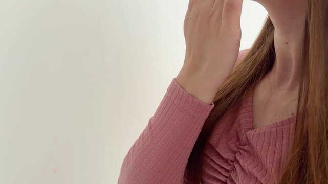 Woman with sore throat pain applying a cream on her neck against a white background while massaging the inflamed and painful area of her body, showcasing health care