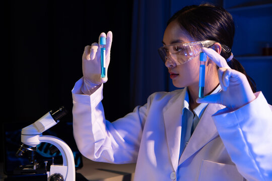 Scientist analyzes a colored liquid to extract the DNA and molecules in the test tubes. Scientists test the chemical reactions of the solution and test biological fluids in test tubes.