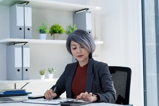 Businesswoman Calculating Finances and Reviewing Charts at Office