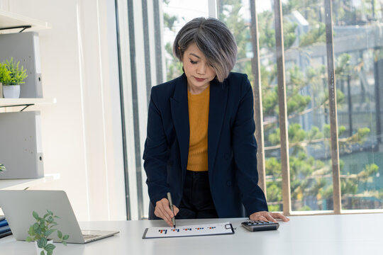 Businesswoman Standing at Desk Analyzing Financial Charts