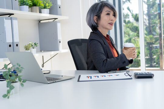 Businesswoman Taking a Coffee Break and Looking Out Window in Office