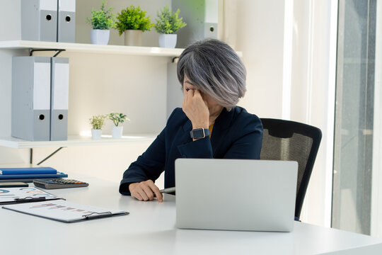 Stressed Businesswoman Rubbing Temples at Office Desk