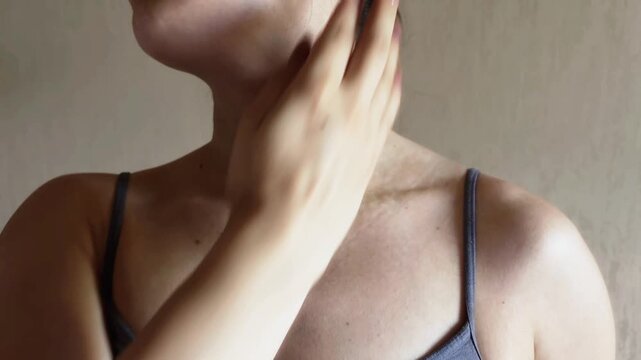 Woman massaging collarbone and neck with a massage ball for pain relief, muscle relaxation, myofascial release, and lymphatic drainage to improve blood circulation