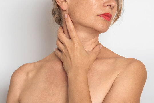Woman touches neck and collarbone area with hand, checks skin and lymph node area. Women's health.