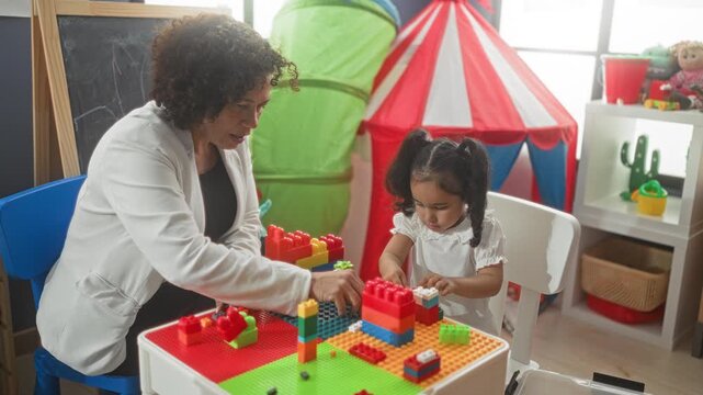 Woman building blocks with little girl in a daycare, guiding hands assembling colorful bricks and focused interaction; early learning nurturing.