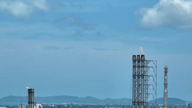 Aerial view of industrial gas flaring stacks releasing flames above an oil and gas refinery, highlighting greenhouse gas emissions, energy transition challenges, safety venting, decarbonization. 4k.
