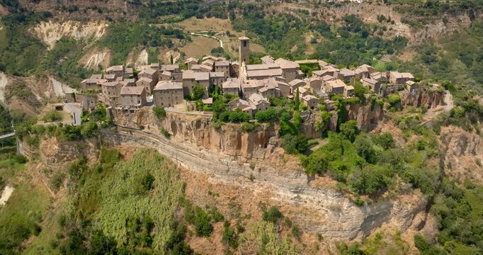 Aerial view of Civita di Bagnoregio, in province of Viterbo, Italy. It's an ancient historic hill town perched atop a cliff surrounded by lush green valleys in the scenic Italian countryside in summer