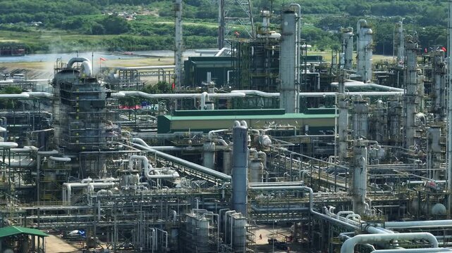 Industrial aerial panorama of a coastal refinery zone displaying complex processing towers, energy infrastructure, the balance between economic development, environmental responsibility, ESG goals.
