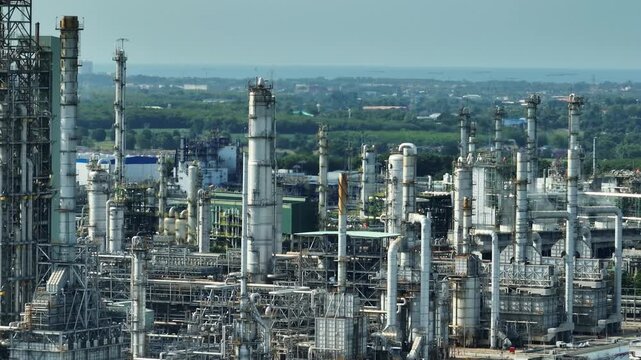 Aerial view of petrochemical distillation columns and refinery facilities highlighting global manufacturing networks, resource efficiency, carbon reduction strategies and modern industrial innovation.