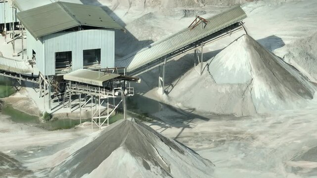 Wide aerial view of aggregate production operations with conveyor belts feeding gravel stockpiles, reflecting heavy industry engineering, construction resource management. 4k.
