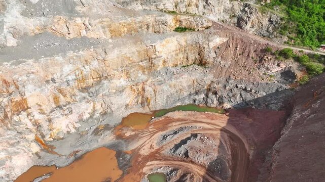 High-altitude aerial shot of a quarry site revealing human-made landscapes, exposed rock formations, and the environmental responsibility required for sustainable mining development. 4k.
