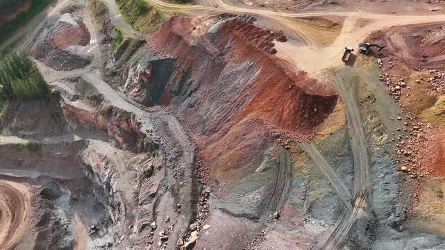 Panoramic drone view of an open-pit mining area showing rock excavation, altered mountain formations, and the complex relationship between economic development and nature preservation. 4k.
