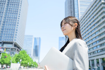 Fototapeta premium ビル街でノートパソコンを使う日本人女性
