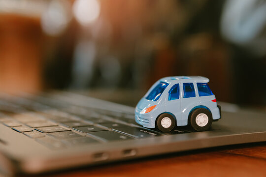 Toy car on laptop keyboard with blurred background and warm light