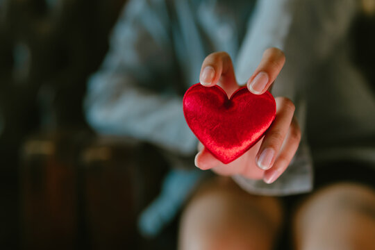 Heart hand red love gift human closeup blurred romantic soft light emotion affection Valentine single finger holding symbol care tenderness passion warmth sweet shiny velvet