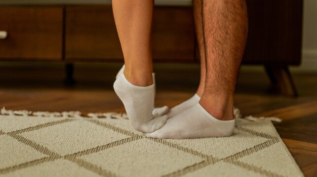 Intimate moment between a couple captured by their feet touching on a rug