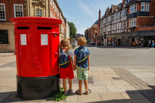 Two children with backpacks beside red postbox on York street