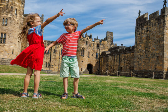 Boy and girl visitors pointing at towers in historic castle wall