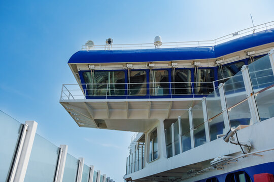 Blue and white ferry deck with glass railings under clear sky