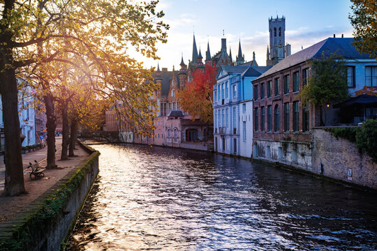 Sunlit canal scene along historic townhouses in Bruges, Belgium