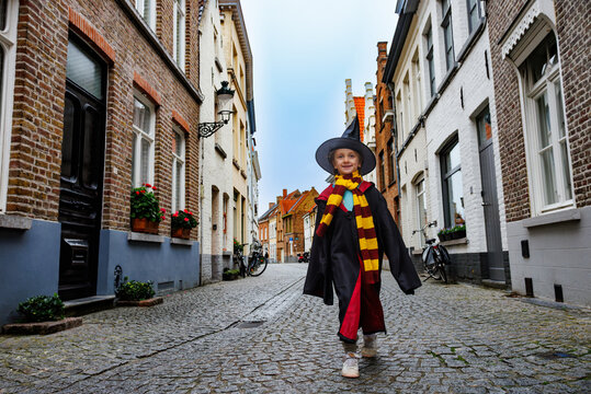 Child girl in wizard costume walking on cobbled street, Bruges