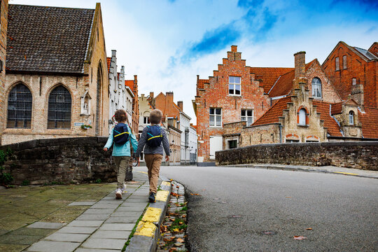 Two kids walk along bridge in historic part of Bruges, Belgium