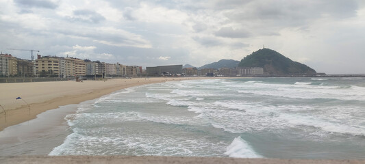 Fototapeta premium Vista general de la costa y la ciudad bajo cielo nublado en San Sebastián, España
