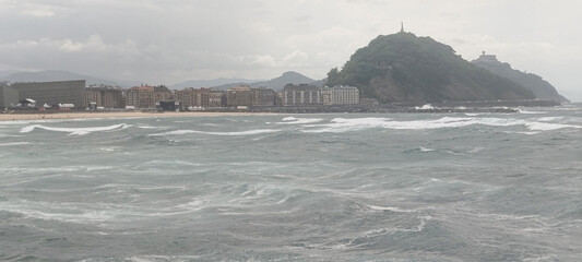 Fototapeta premium Vista general de la costa y la ciudad bajo cielo nublado en San Sebastián, España