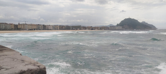 Fototapeta premium Vista general de la costa y la ciudad bajo cielo nublado en San Sebastián, España